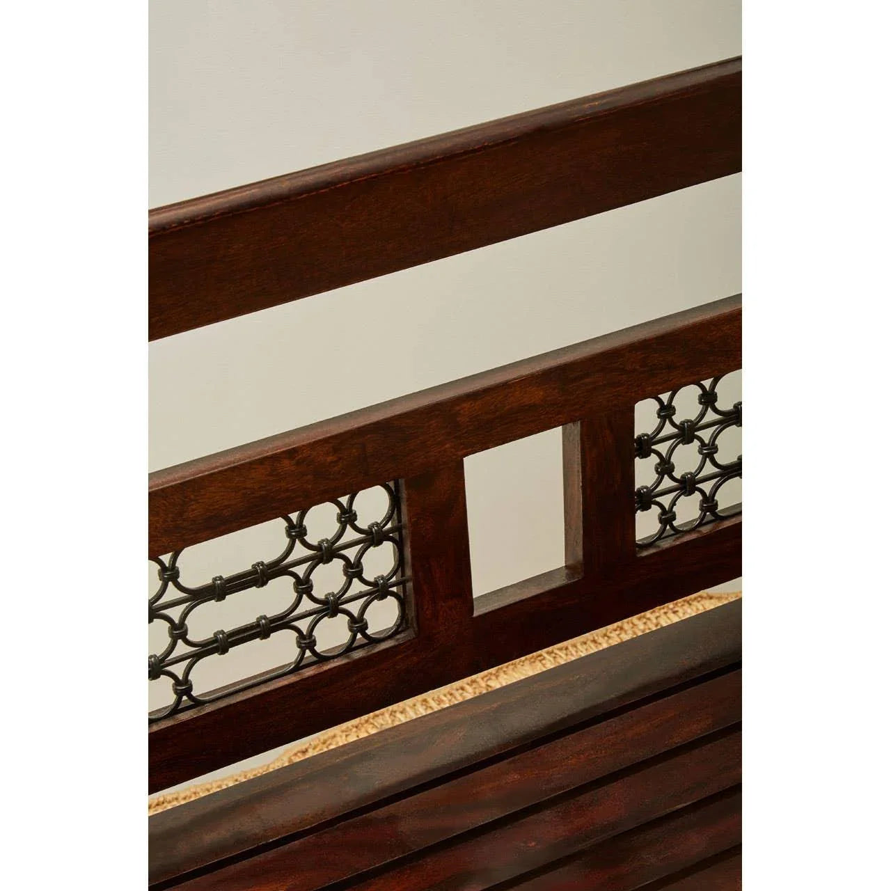 Dark wood bench backrest with decorative metal lattice panels and slatted seat detail
