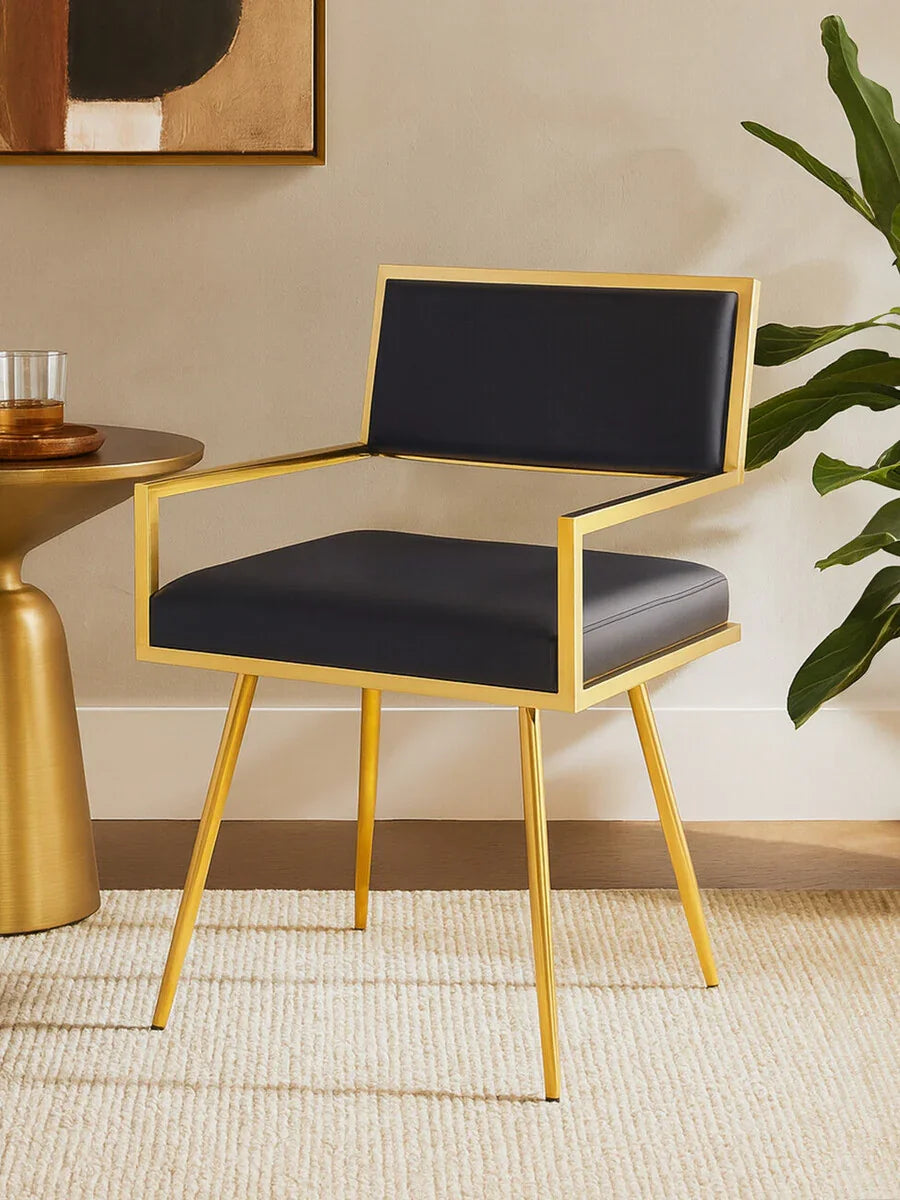 Modern dining chair with gold metal frame and black cushioned seat on cream rug