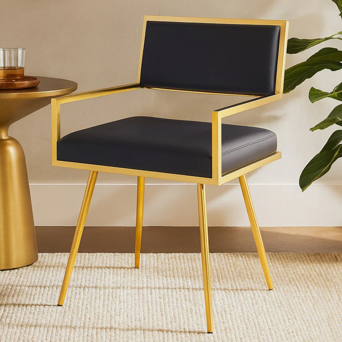 Modern accent chair with gold metal frame and black upholstered seat on cream rug