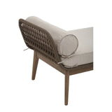 Corner view of rattan armchair with grey cushion and bolster pillow on wooden legs
