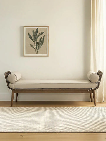 Beige upholstered bench with bolster cushions on wooden legs in minimalist living room