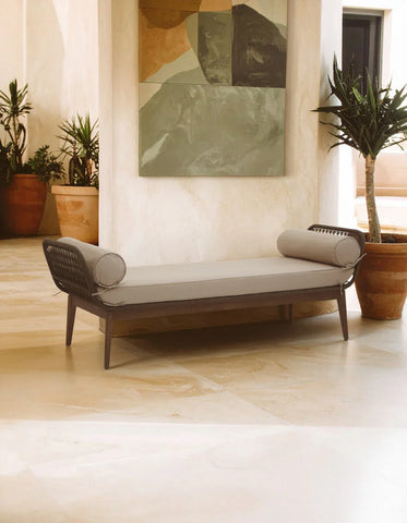 Modern outdoor daybed with grey cushions and rope sides on stone patio