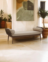 Modern outdoor daybed with grey cushions and rope sides on stone patio