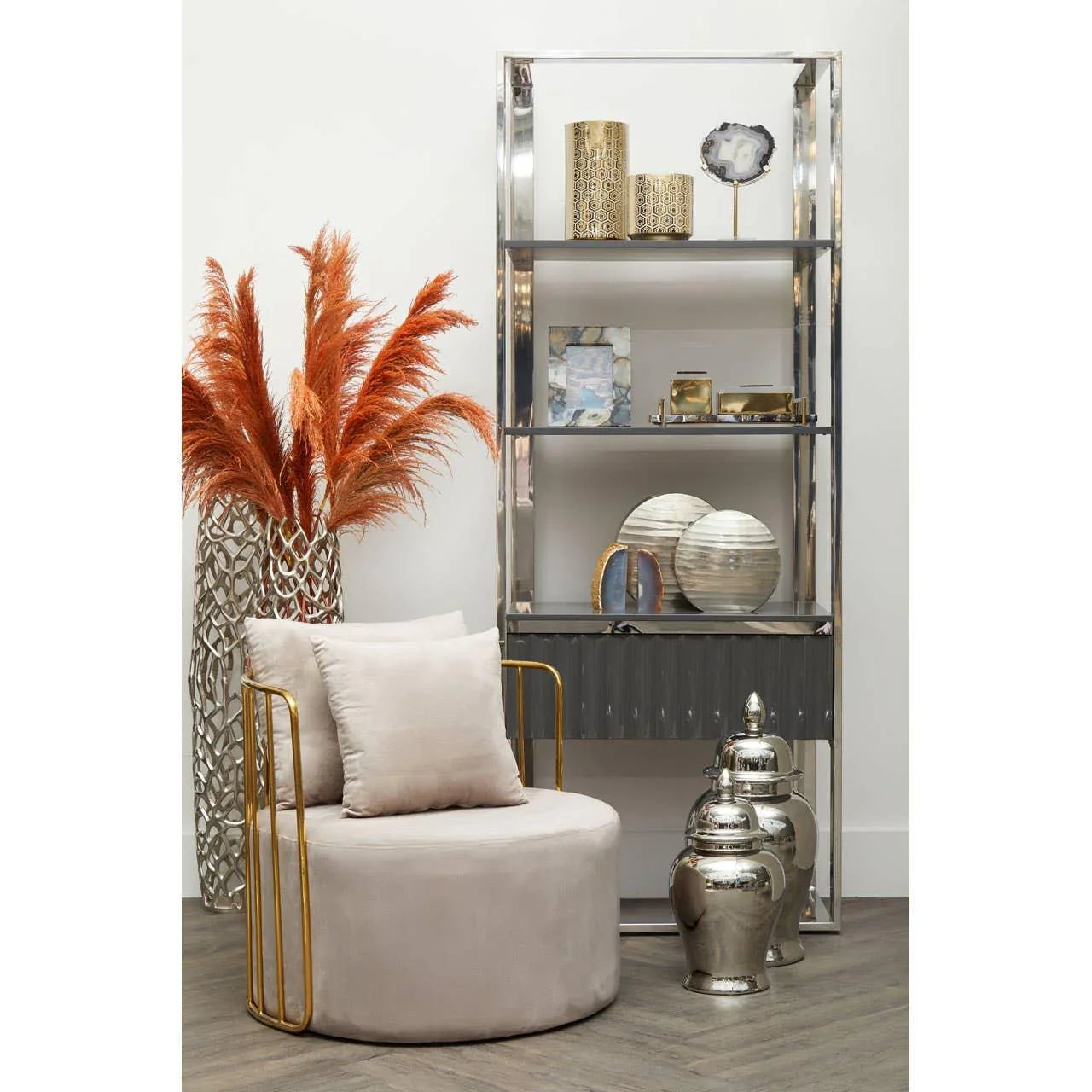Modern accent chair with gold arms, plush cushions, and chrome shelving with decor items