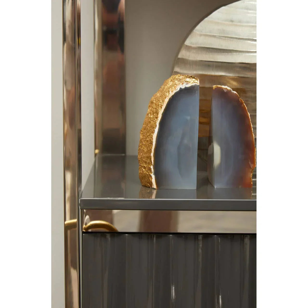 Blue and gold agate bookends on glossy modern shelf