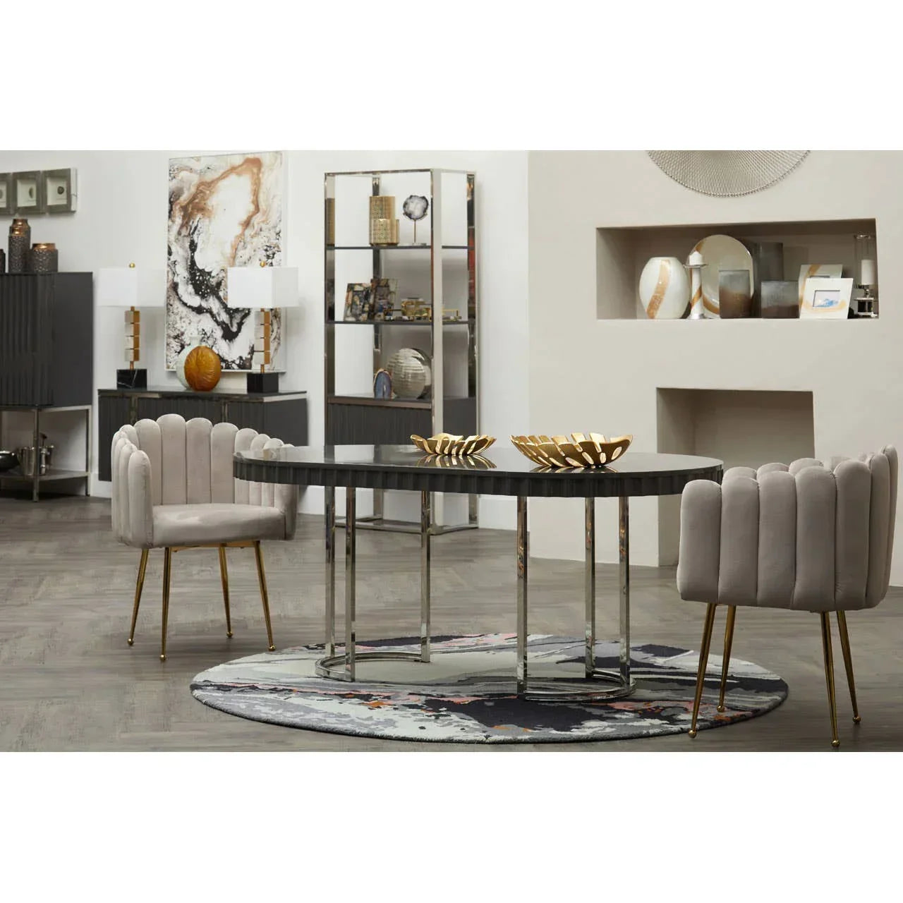 Modern dining table with black top and chrome legs, velvet chairs, and gold decor bowls