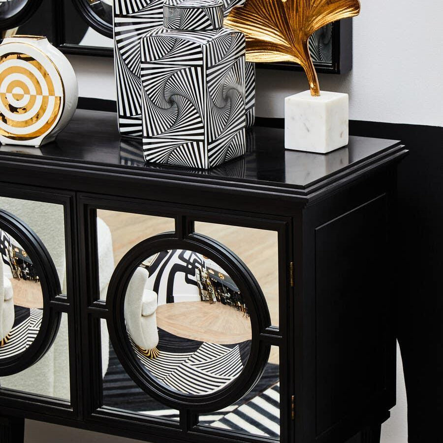 Black mirrored sideboard with geometric vases, gold leaf ornament, monochrome decor accents