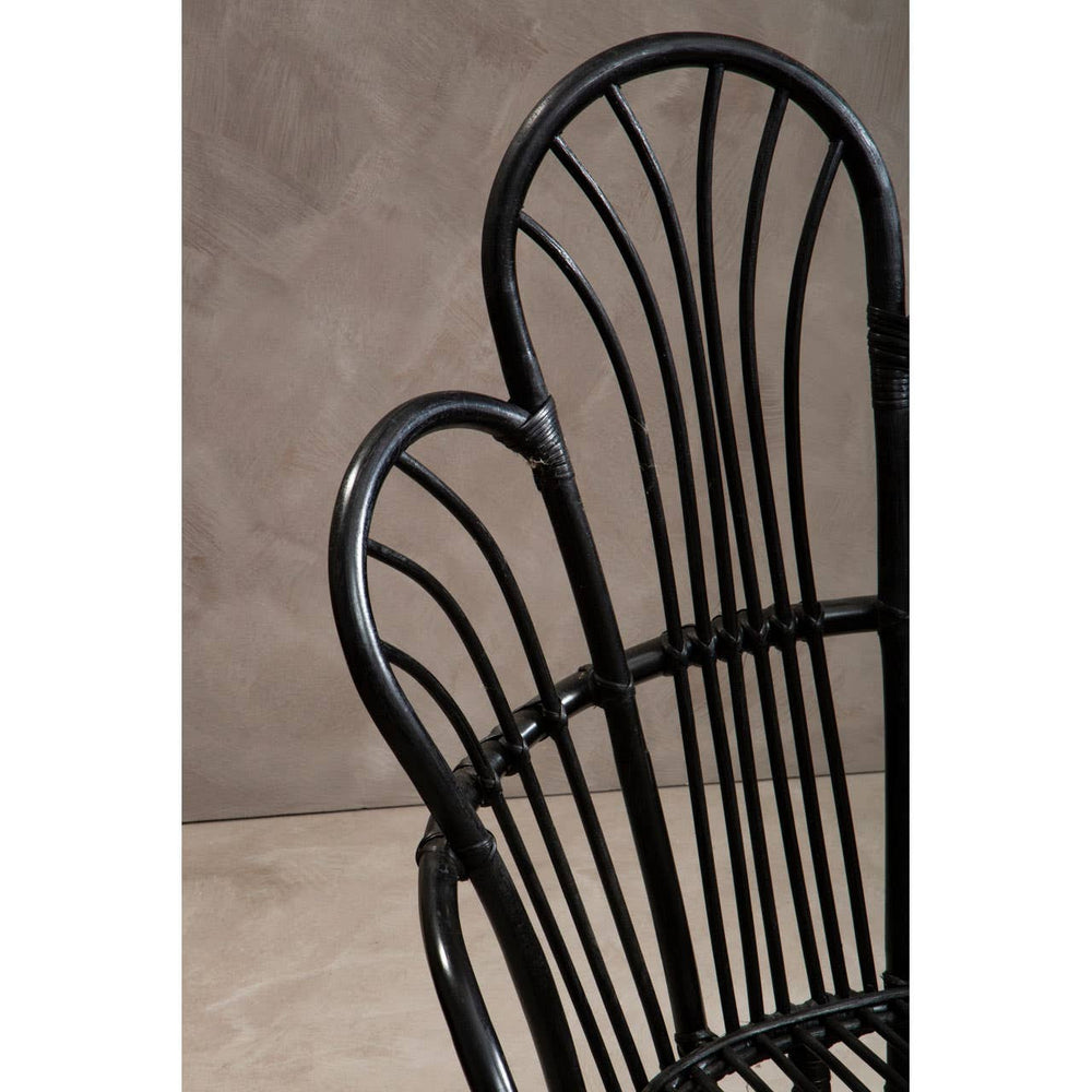 A close-up view of a black metal chair featuring a scalloped back design, with natural rattan detailing. The chair has slender vertical slats and a smooth finish, set against a neutral textured background