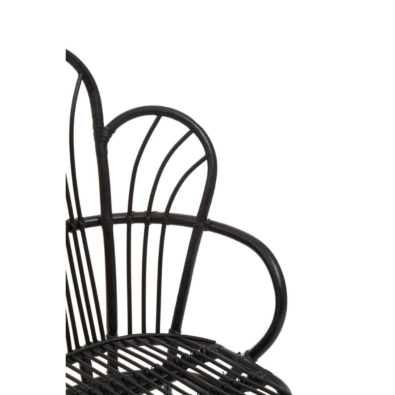 A black metal chair featuring a scalloped back design, with natural rattan accents. The chair has a sleek, modern silhouette and is shown from a side angle, highlighting its curved lines and open structure