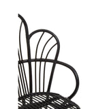 A black metal chair featuring a scalloped back design, with natural rattan accents. The chair has a sleek, modern silhouette and is shown from a side angle, highlighting its curved lines and open structure