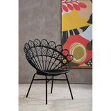 A black natural rattan peacock chair with a distinctive fan-shaped backrest, featuring curved lines and a sturdy metal frame. The chair is positioned on a light-colored floor against a textured gray wall, with a colorful abstract artwork in the background