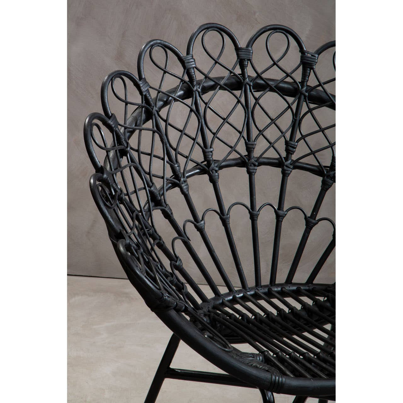 Black natural rattan peacock chair featuring a distinctive fan-shaped backrest with intricate woven patterns, supported by a sturdy frame. The chair is set against a neutral-toned background, highlighting its elegant design and craftsmanship