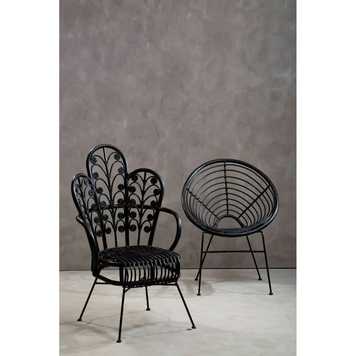 Black rattan accent chairs with decorative backrest and curved seat on neutral background