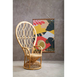 Curved chair made of natural rattan with a woven design, featuring a round seat and a tall backrest. The chair is positioned next to a colorful abstract wall art piece against a textured gray wall