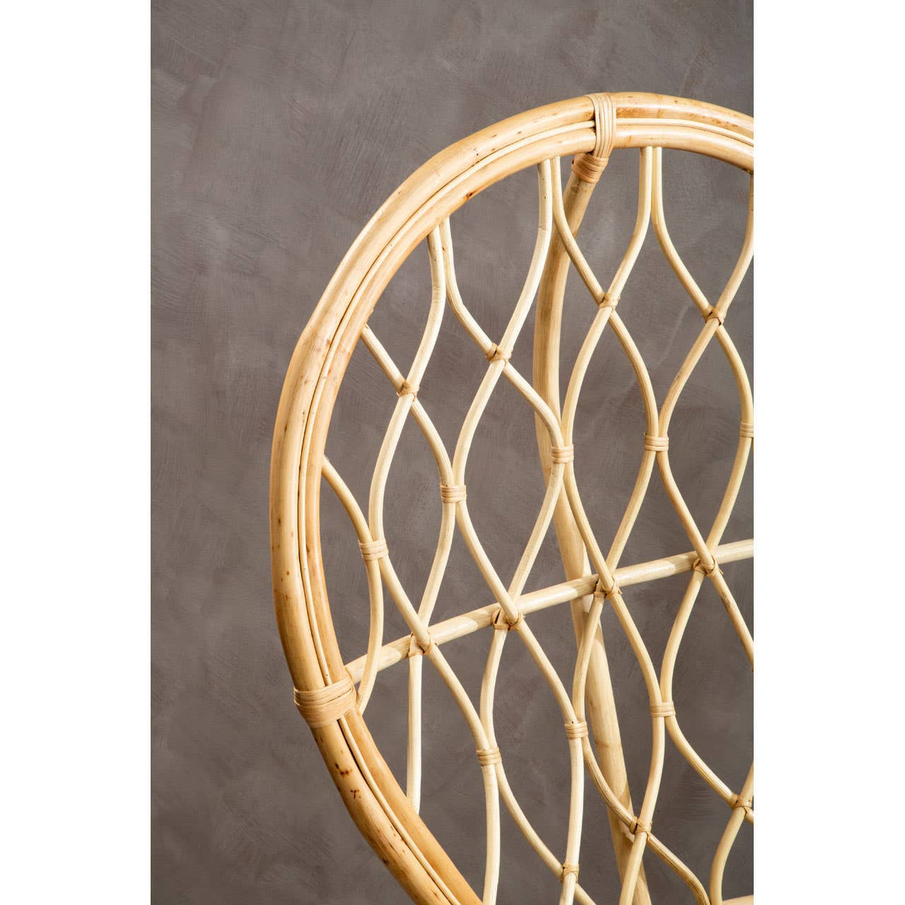 Curved natural rattan chair featuring a unique woven pattern, showcasing a light wood finish against a textured gray background