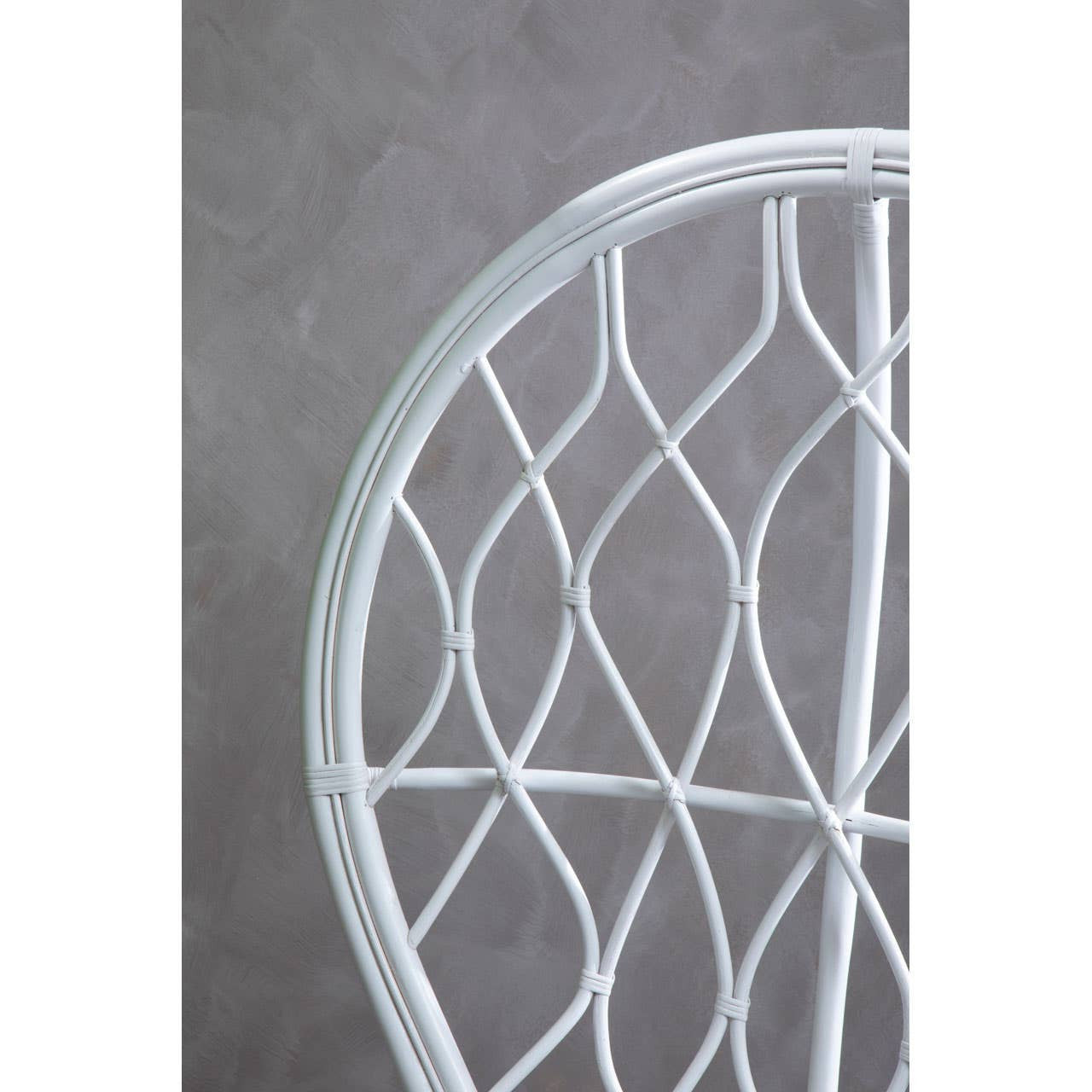 Curved chair made of natural rattan, featuring a grey and white color scheme with a geometric woven pattern. The background is a textured grey surface, highlighting the chair's design