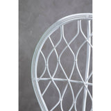 Curved chair made of natural rattan, featuring a grey and white color scheme with a geometric woven pattern. The background is a textured grey surface, highlighting the chair's design