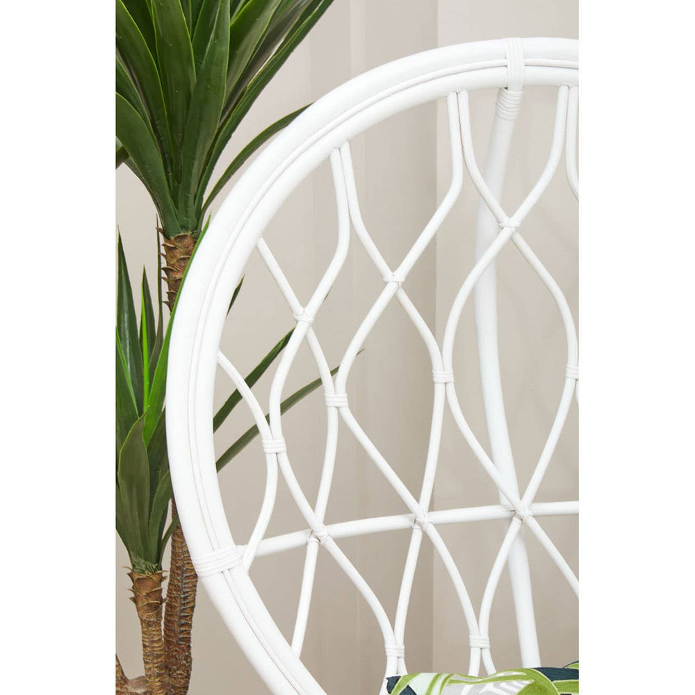 Curved chair made of natural rattan featuring a grey and white color scheme, showcasing a geometric pattern in the backrest. A green plant is partially visible in the background, adding a touch of nature to the setting