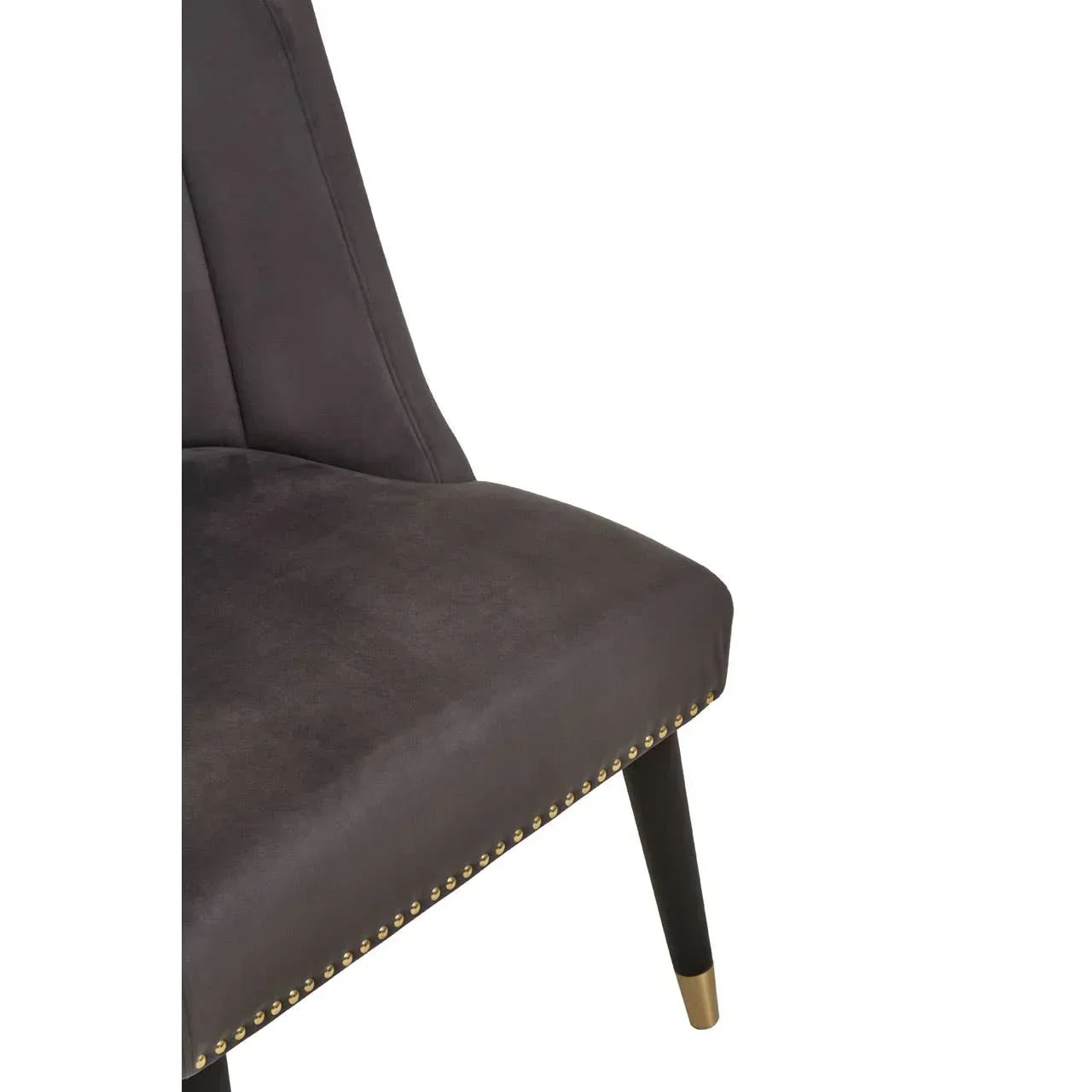 Close-up of dark grey velvet dining chair with gold stud detail and tapered wooden leg