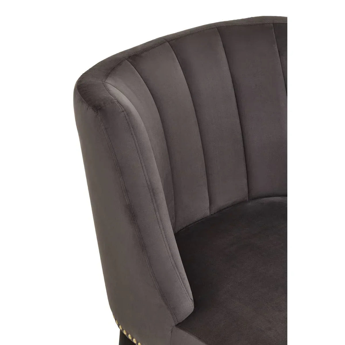 Grey velvet armchair with curved backrest and vertical channel tufting, close-up view