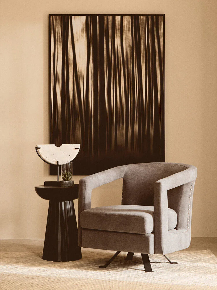 Grey swivel accent chair beside black side table and abstract wall art in modern living room