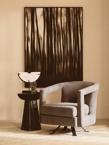 Grey swivel accent chair beside black side table and abstract wall art in modern living room