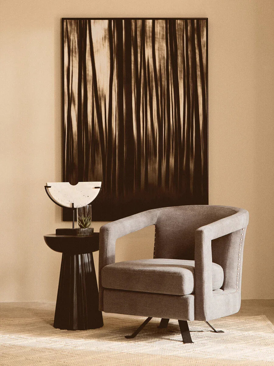 Grey swivel accent chair beside black side table and abstract wall art in modern living room