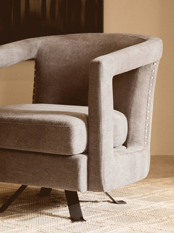 Modern grey fabric accent chair with metal legs and stud detailing on carpet