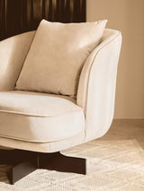 Beige velvet armchair with cushion and black swivel base on textured rug