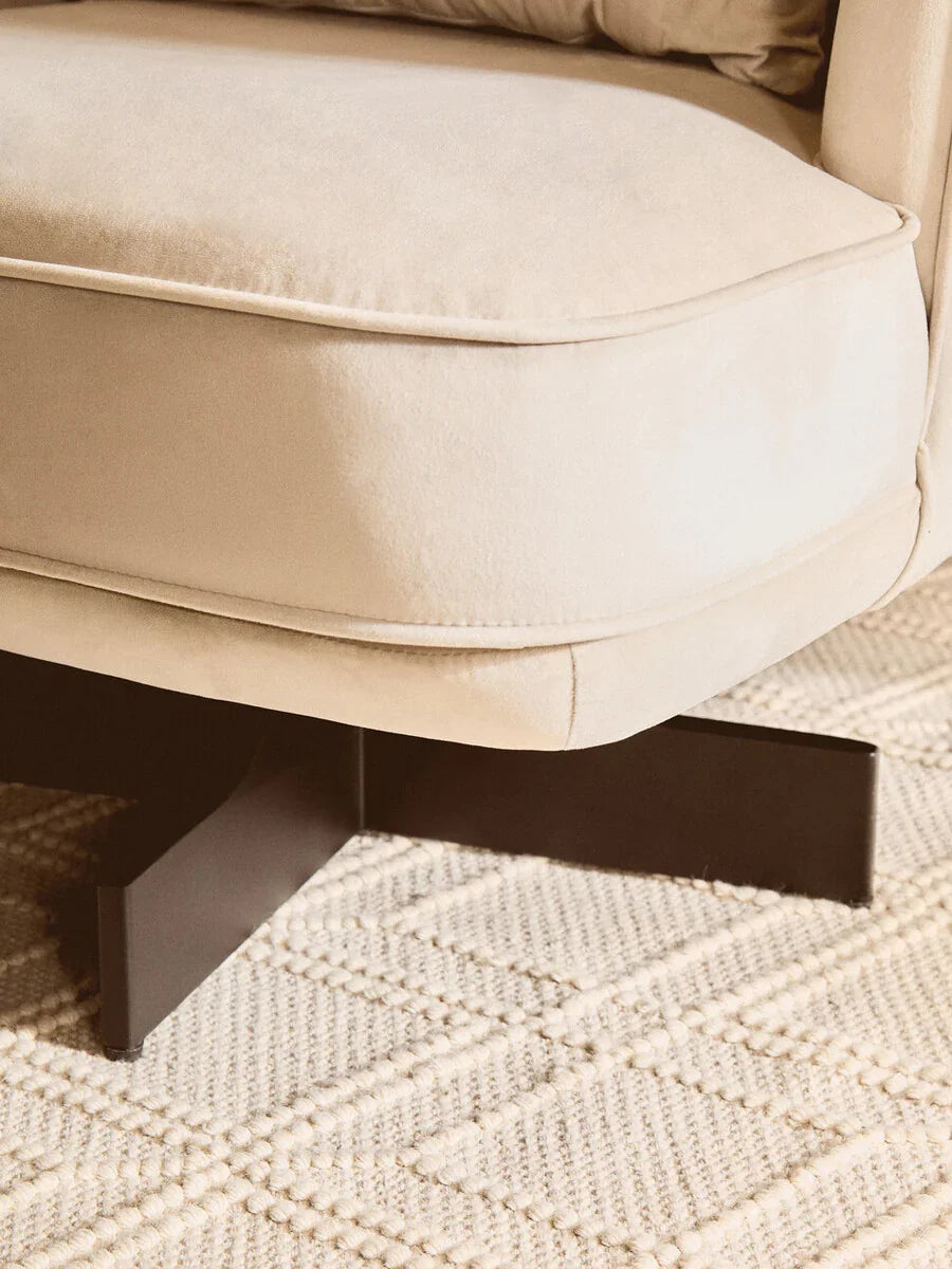Beige fabric sofa seat with black metal leg on textured cream rug