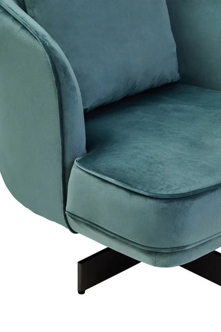 Closeup of teal velvet armchair seat with cushion and black metal leg