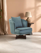 Blue velvet accent armchair with cushion on modern tiled floor beside round side table and lamp