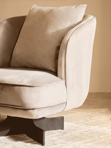 Beige fabric armchair with cushioned seat and back, black swivel base on patterned rug