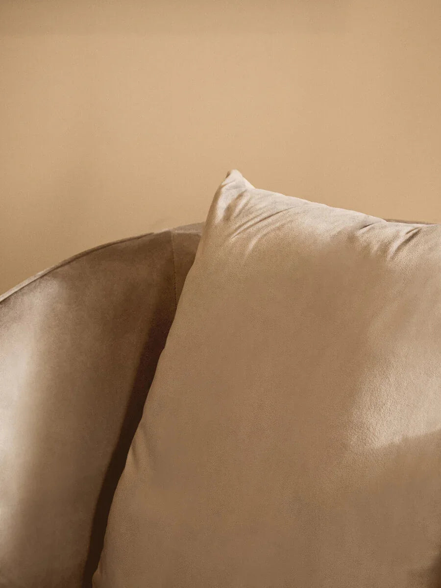Close-up of beige velvet sofa cushion with soft texture and curved armrest detail