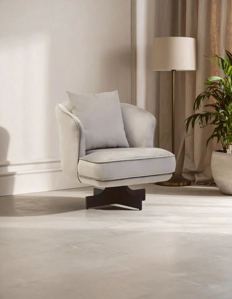 Light grey accent chair with cushion and dark wood base in modern living room setting