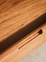 Close-up view of the Lyon Rattan and Oak Wood 2 Door Wardrobe, highlighting the smooth wooden surface and a sleek drawer with a minimalist handle. The natural grain of the oak wood is visible, showcasing its warm tones and texture