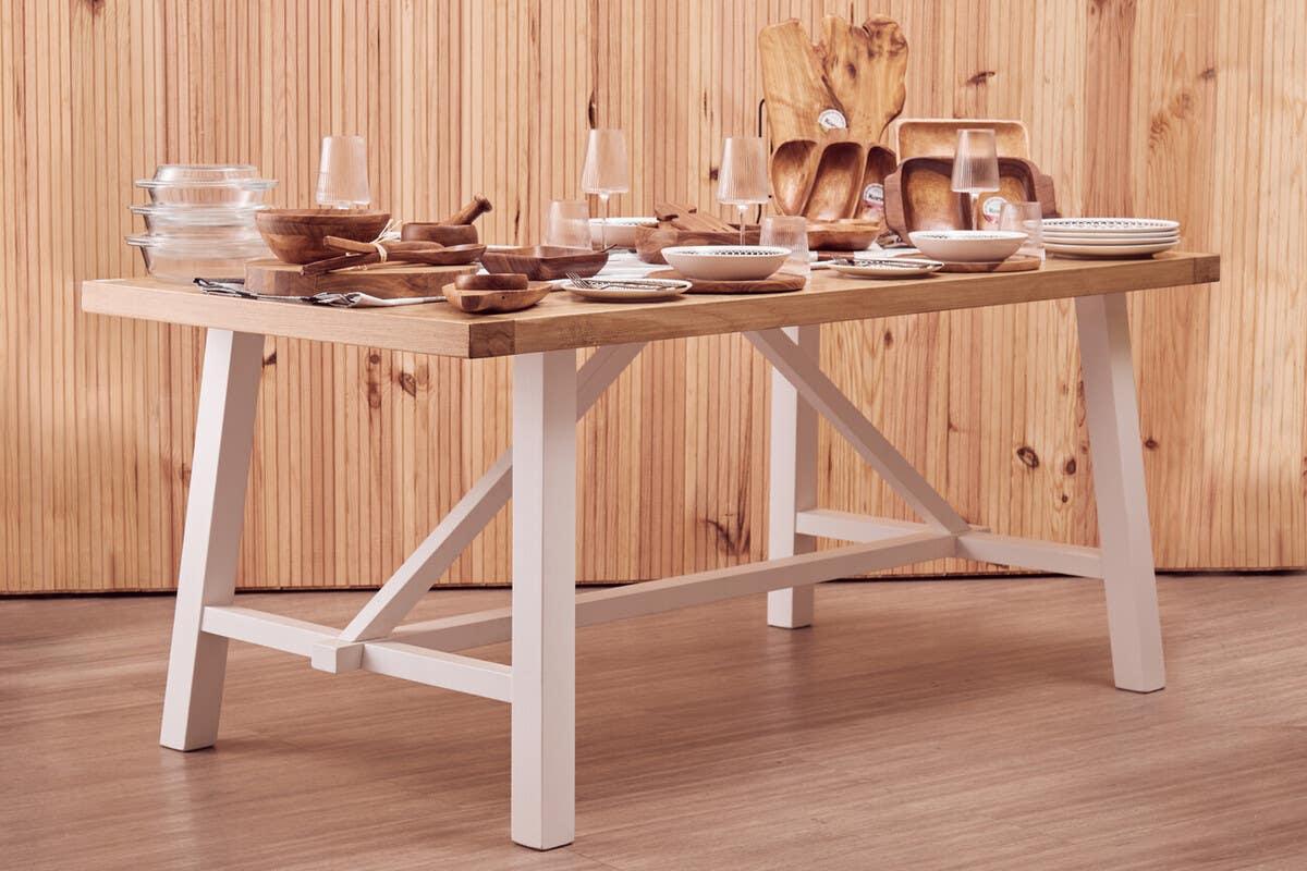 Rectangular wooden dining table with white legs set for a meal, featuring glassware and plates