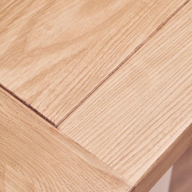 Closeup of light oak dining table corner showing wood grain and smooth finish