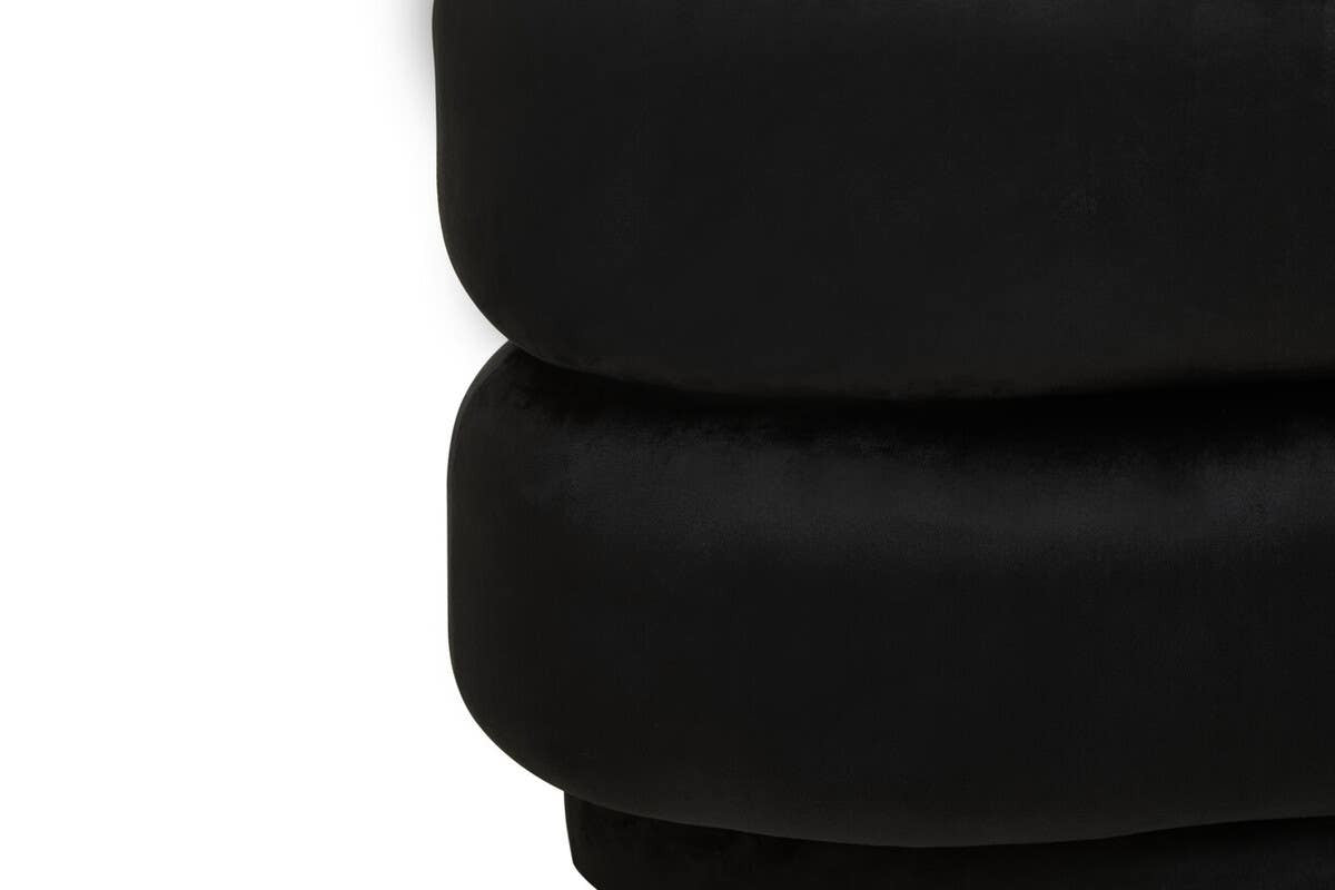 Black velvet oval pouffe with a smooth, plush texture, featuring a rounded shape and a stacked design. The surface appears soft and inviting, suitable for use as a footrest or additional seating