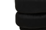 Black velvet oval pouffe with a smooth, plush texture, featuring a rounded shape and a stacked design. The surface appears soft and inviting, suitable for use as a footrest or additional seating