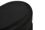Black velvet oval pouffe with a smooth, rounded top and a sleek design, showcasing a rich texture and elegant appearance