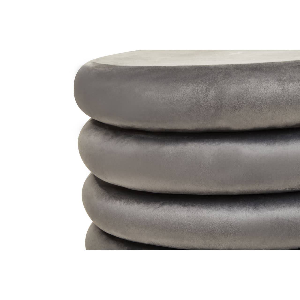 A close-up view of three stacked round pouffes in a soft grey velvet fabric, showcasing their smooth texture and rounded edges