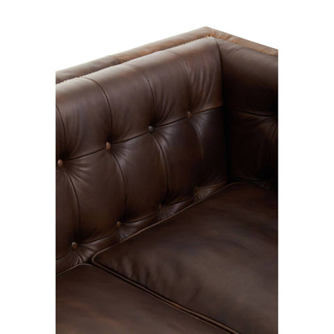 Close-up view of the armrest and backrest of a dark brown leather Chesterfield sofa, featuring deep button tufting and a smooth, polished finish. The rich color and texture highlight the modern design and luxurious feel of the furniture
