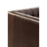 Close-up view of the corner of a dark brown leather Chesterfield sofa, showcasing the tufted design and smooth finish of the leather upholstery. The sofa features a modern silhouette with clean lines and a sturdy frame