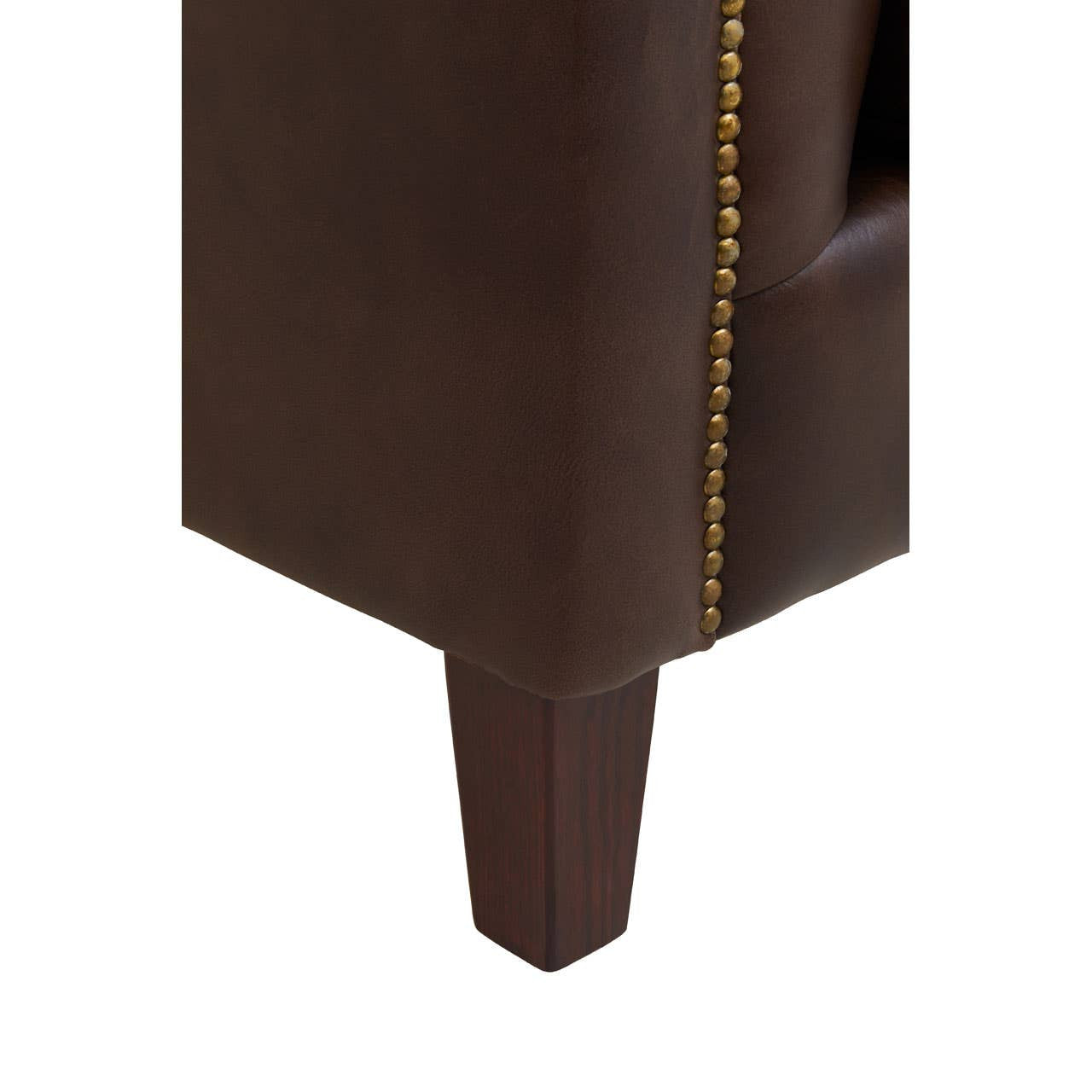 Close-up view of the leg and side of a dark brown leather Chesterfield sofa, showcasing the rich texture of the leather and decorative gold nailhead trim along the edge. The leg is wooden and tapered, providing a modern touch to the classic design