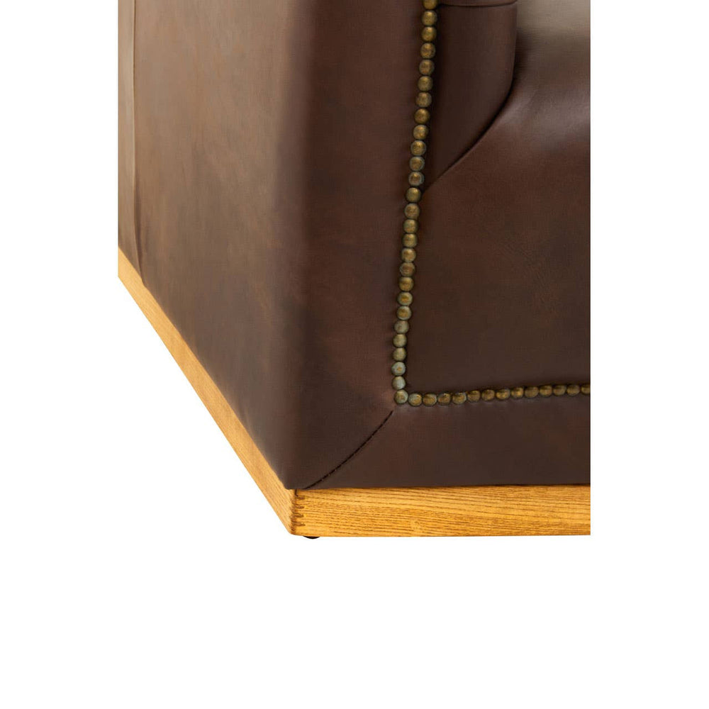 Corner view of a dark brown leather sofa featuring a modern Chesterfield design, showcasing a wooden base and decorative stitching along the edges