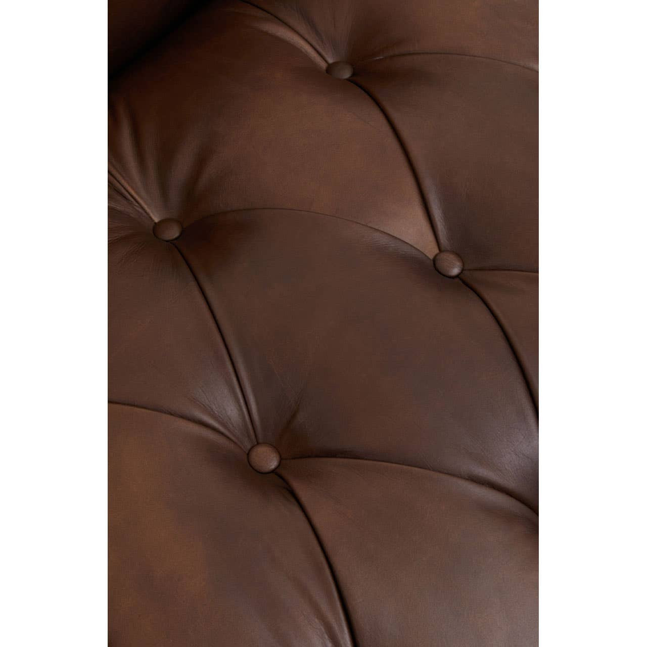 Close-up view of the tufted dark brown leather upholstery of a Chesterfield sofa, showcasing the rich texture and button detailing