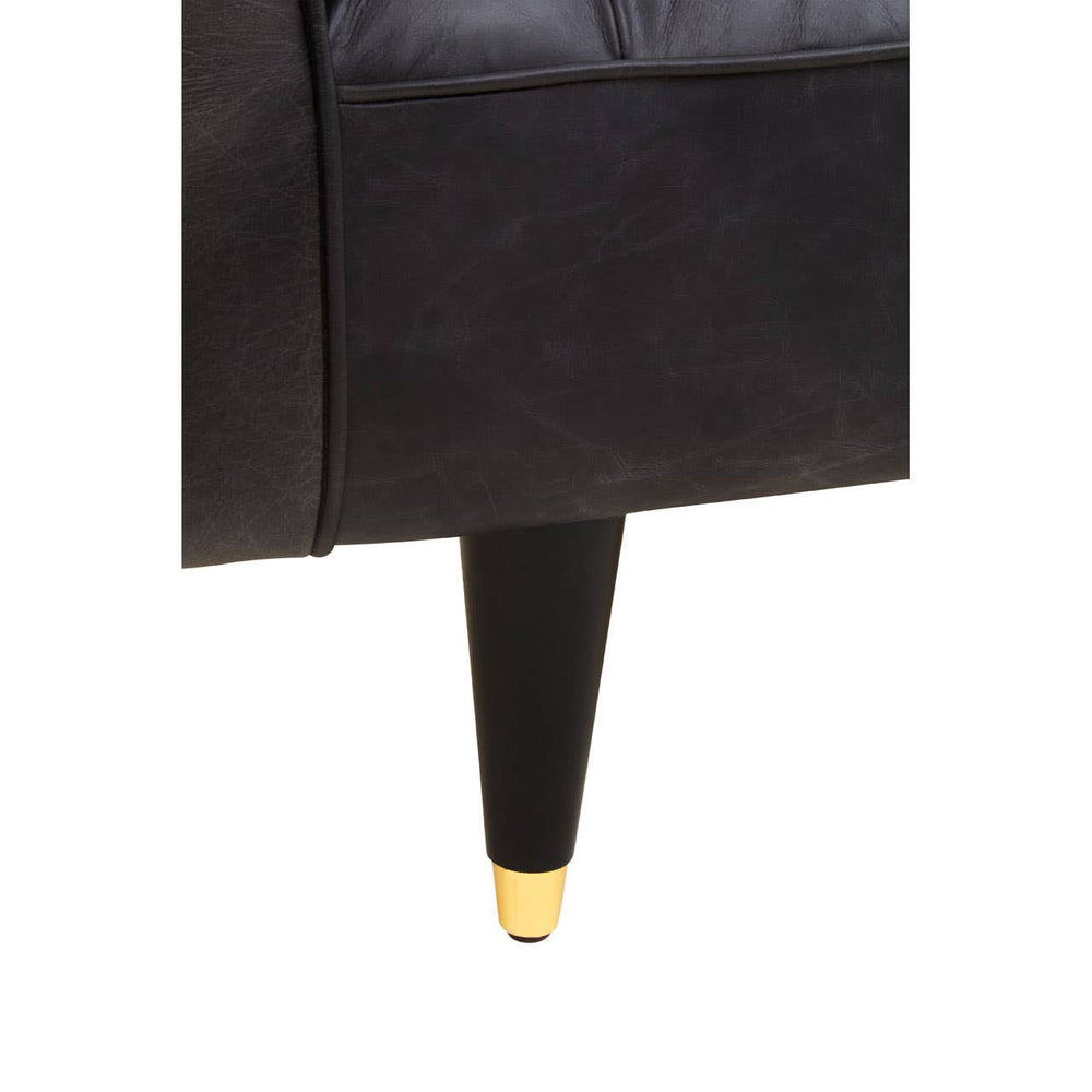 Black leather sofa with flared arms and a sleek design, featuring tapered legs with gold accents. The upholstery appears smooth and luxurious, highlighting the modern aesthetic of the piece