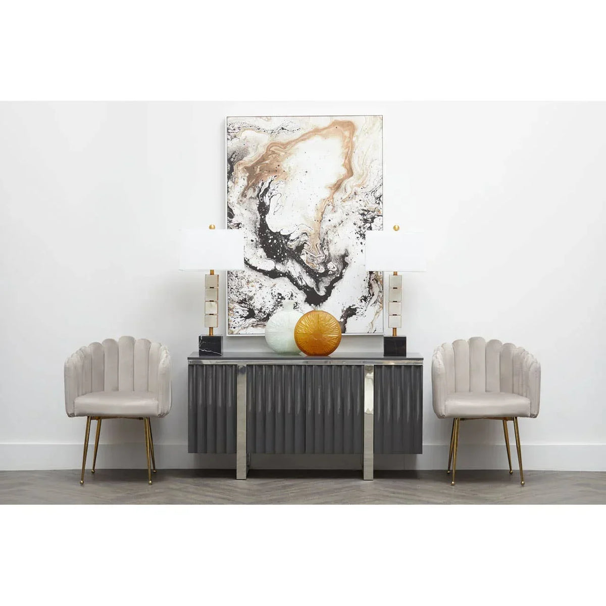 Modern sideboard with marble lamps, abstract art, and two beige velvet accent chairs