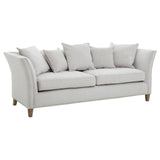Three-seat sofa upholstered in light grey fabric, featuring a curved backrest and armrests. The sofa is adorned with several plush cushions for added comfort and is supported by wooden legs